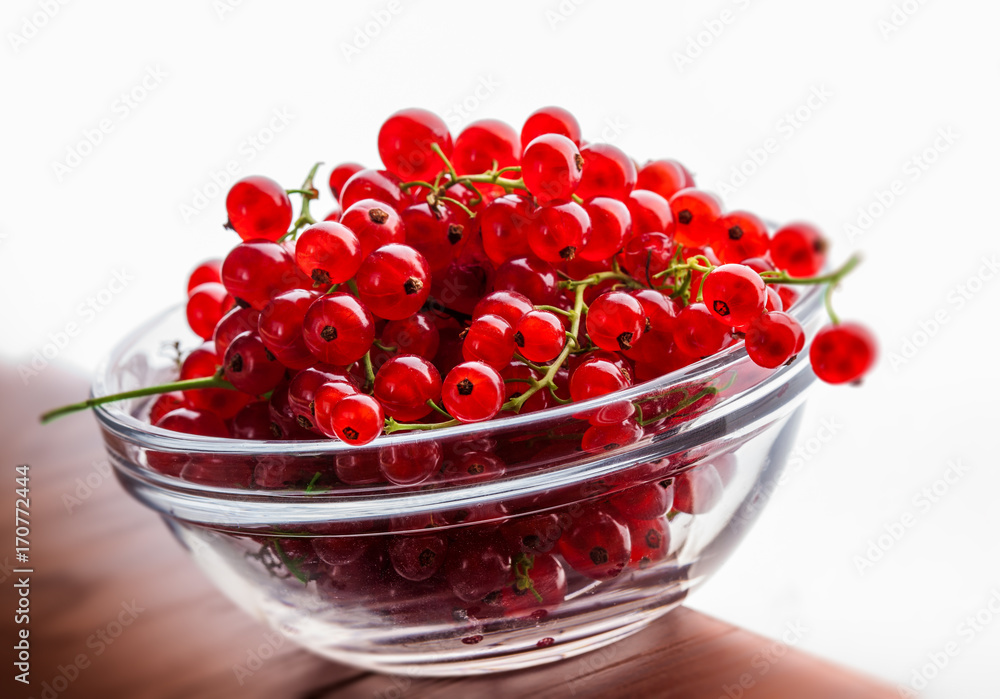 Red currant in glass jar on old rustic wooden table and white background in studio Red currant in glass jar on old rustic wooden table and white background in studio
