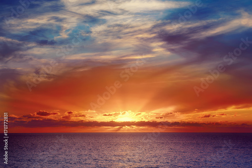 Beautiful colorful sunset at the sea with dramatic clouds and sun shining. Beauty world natural outdoors travel background © Roxana