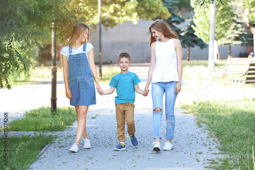 Happy lesbian mothers and foster son walking in park. Adoption concept © Africa Studio