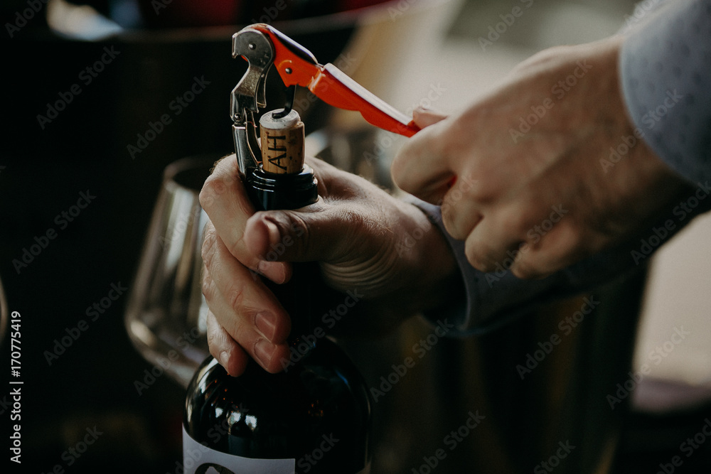 Sommelier opening wine bottle in the wine cellar - obrazy, fototapety, plakaty 