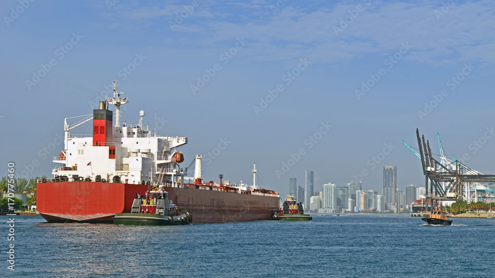 Ship being guided by two tug boats on its way into the Port of Miami to pick up a cargo of containers,