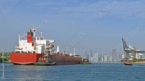 Ship being guided by two tug boats on its way into the Port of Miami to pick up a cargo of containers 