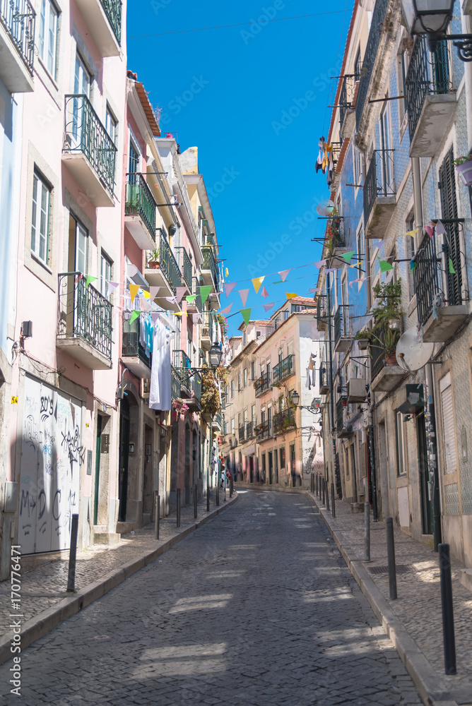 Lisbon in Portugal, typical street, sloping alley with colored houses and typical pavement 
