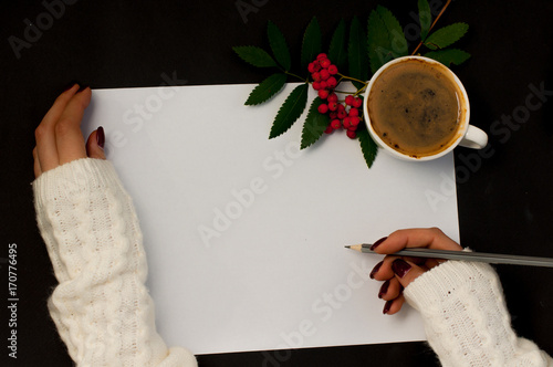 a cup of coffee rowan or a shoal on a black background and the hand writes on the sheet an empty space for the text