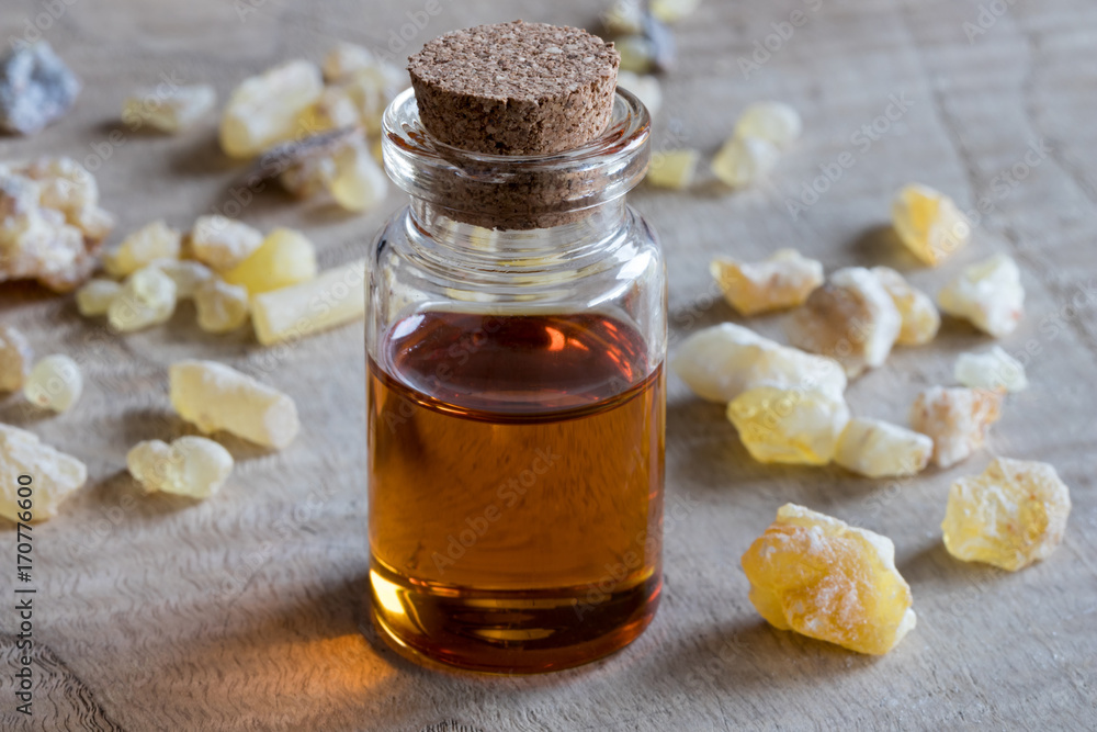 A bottle of frankincense essential oil on a wooden background A bottle of frankincense essential oil on a wooden background