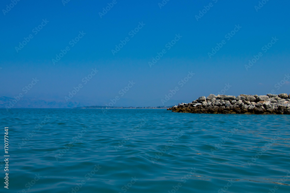  turquoise sea water crashing on calcium white stones against the azure sky on a sunny day