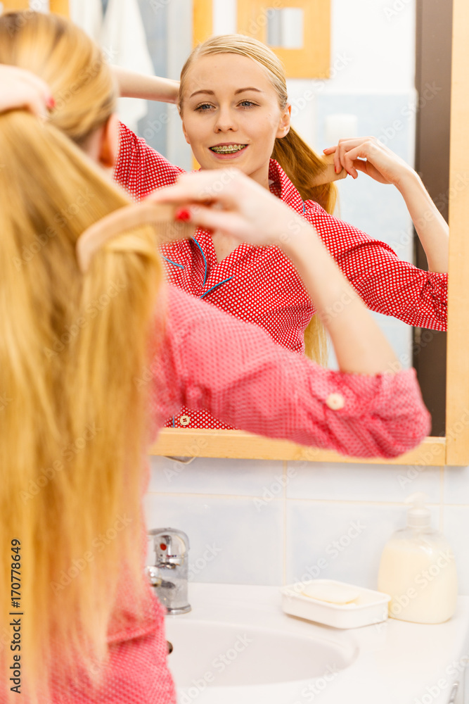 Woman combing her long hair in bathroom Woman combing her long hair in bathroom