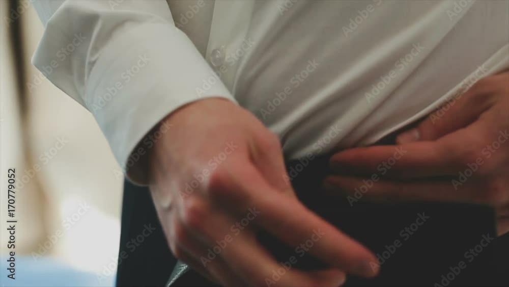 Businessman puts on a belt on trousers Businessman puts on a belt on trousers