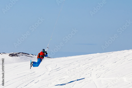 Snowboarder with a kite on fresh snow in the winter in the tundra of Russia against a clear blue sky. Teriberka, Kola Peninsula, Russia. Concept of winter sports snowkite.