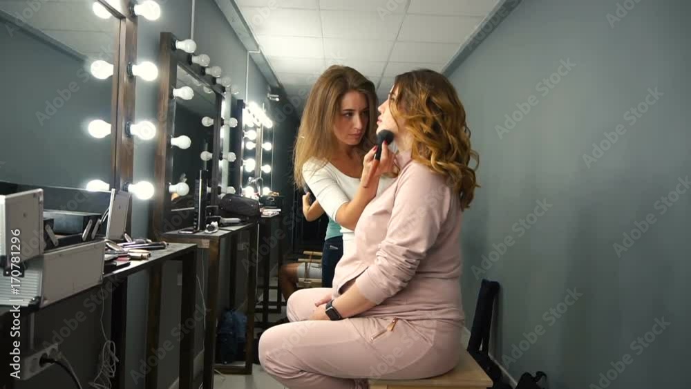 Applying blush makeup with brush to cheekbones of young woman. Applying blush makeup with brush to cheekbones of young woman.