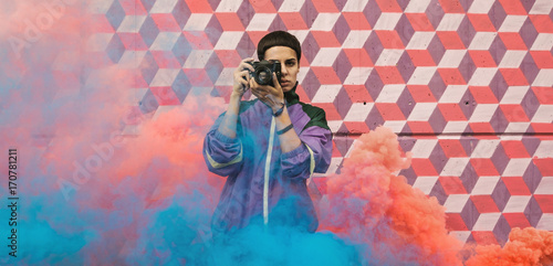 Hip young girl with old analog camera surrounded with smoke.