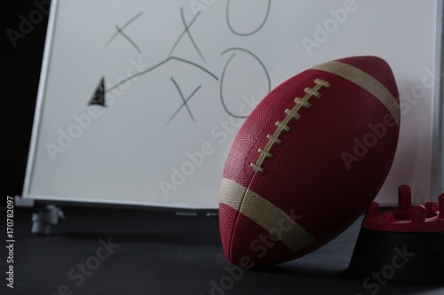 American football resting on holder and game strategy drawn on