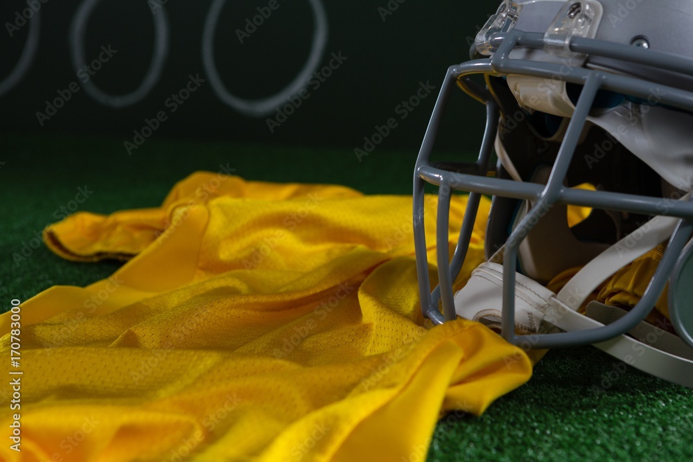 Close-up of American football head gear and jersey lying on