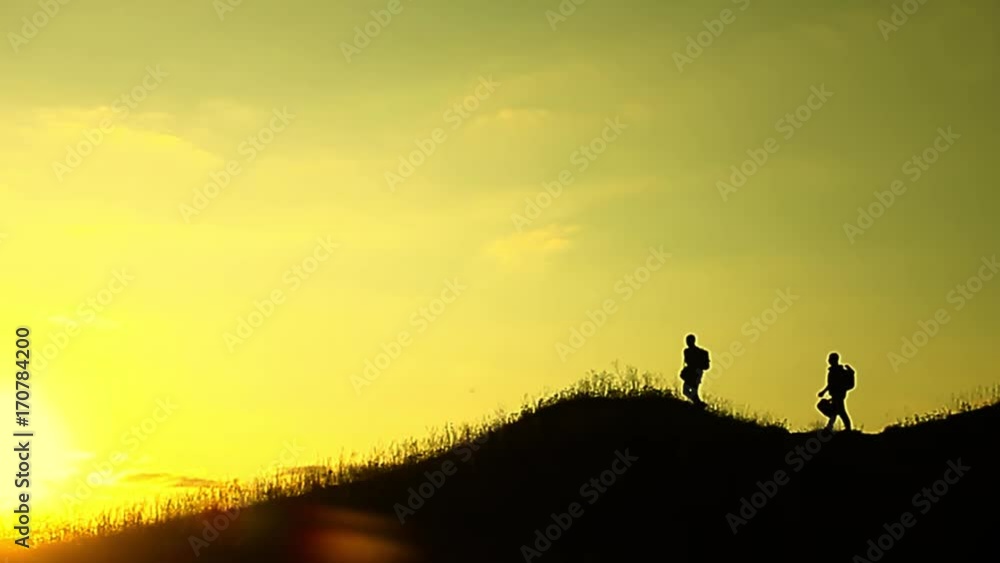 The Silhouette of two man standing on the top of mountain with Backpacks and other Gear expressing Energy and Happiness. Travel concept. The Silhouette of two man standing on the top of mountain with Backpacks and other Gear expressing Energy and Happiness. Travel concept.