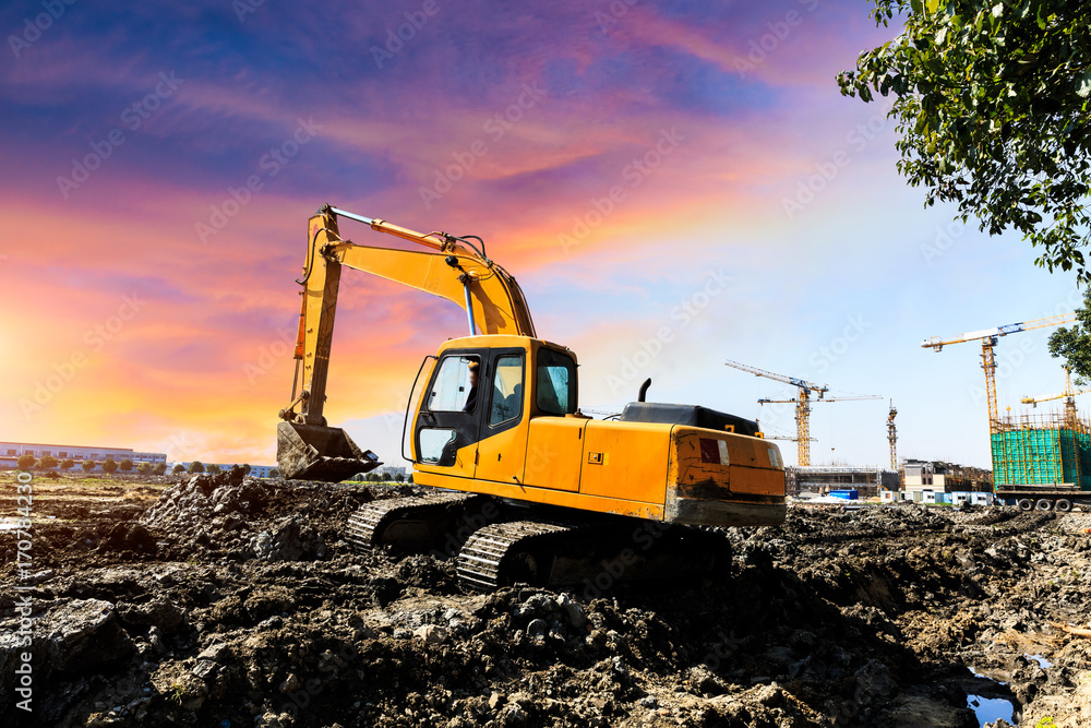 Excavator working at construction site on sunset Excavator working at construction site on sunset