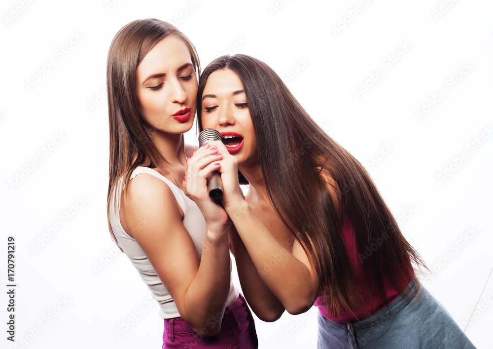 lifestyle and people concept: Happy girls friends with microphone over white background lifestyle and people concept: Happy girls friends with microphone over white background