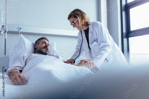 Doctor examining patient pulse in hospital room