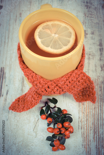 Vintage photo, Cup of tea with lemon wrapped woolen scarf, warmin beverage for flu or cold photo