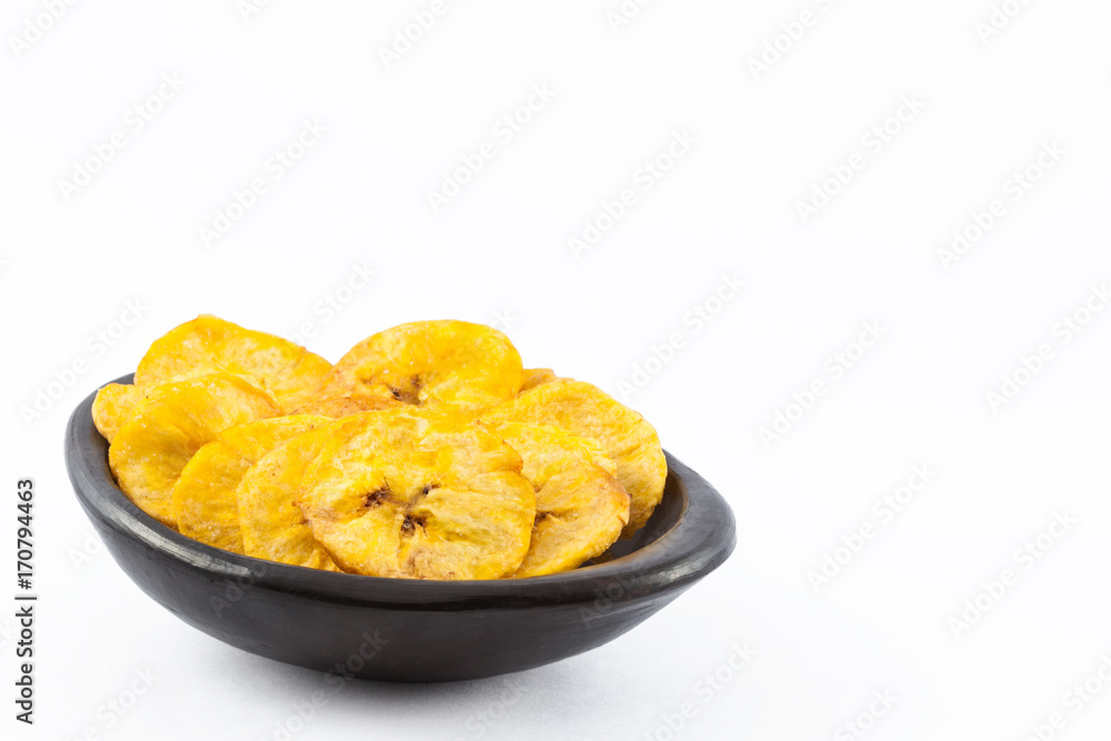 Plantain fried coins in a traditional black clay bowl isolated on white background Plantain fried coins in a traditional black clay bowl isolated on white background