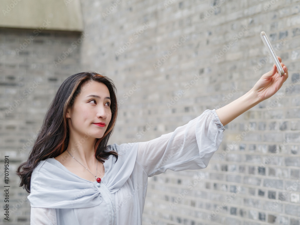 Beautiful Asian woman taking selfie using smart mboile phone.