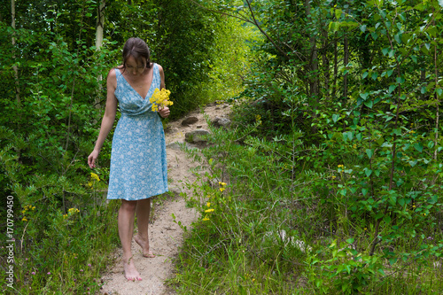 Young woman in romantic blue dress with yellow flowers in the mountains © allenkayaa