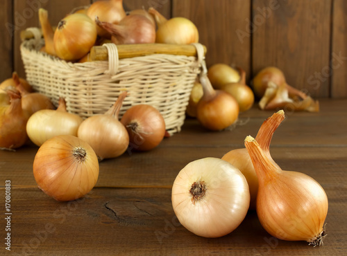 Raw onion in basket and on a wooden table