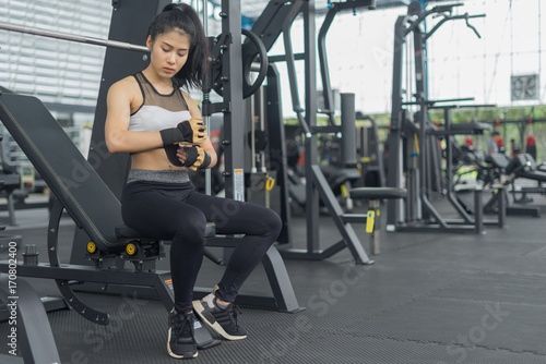 Fitness woman in training put fitness Gloves in gym