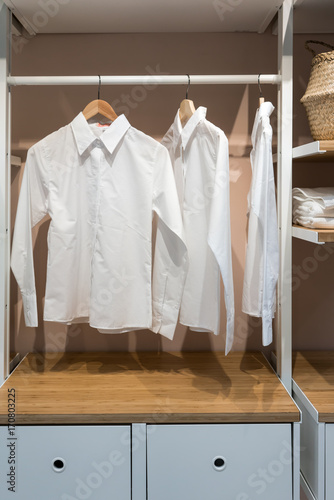 White basic shirts hanging in walk in closet with drawer