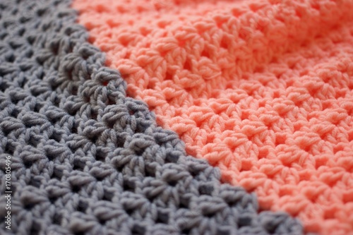a close-up of a simple beige crochet pattern. Texture of Pink and Gray crochet yarn textile as background. Top view. Vertical direction of threads.