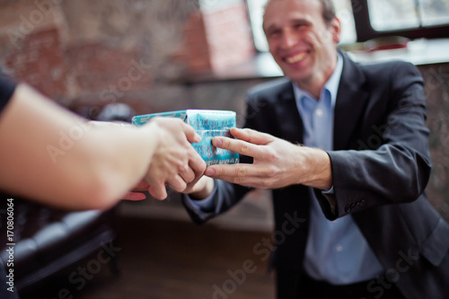 man gives a woman a gift for the New Year. Hands of woman receiving gift in blue box. A smiling man gives a Christmas present.