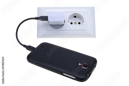 Black Smart Phone With Plugged Charger To Electric Outlet isolated on white background with clipping path.