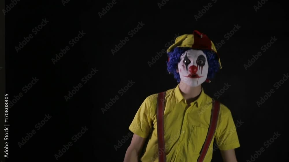 A scary clown makes fast head and torso movements. A scary clown makes fast head and torso movements.