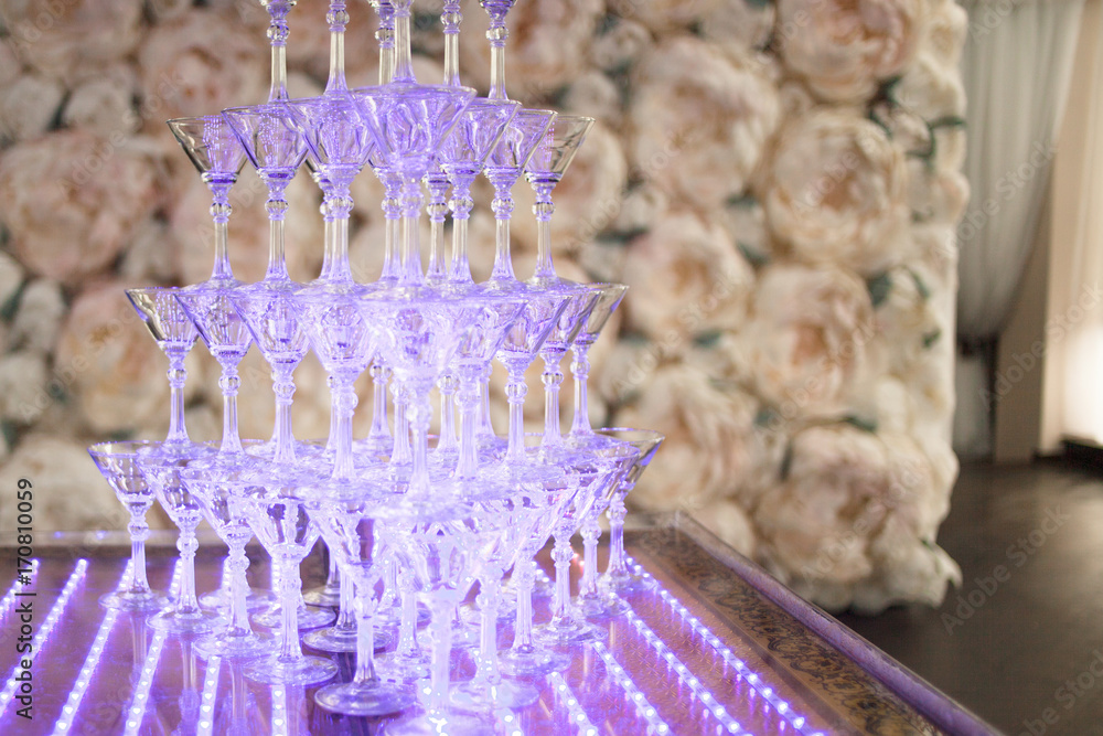 Pyramid from glasses of champagne on wedding party. Floral background