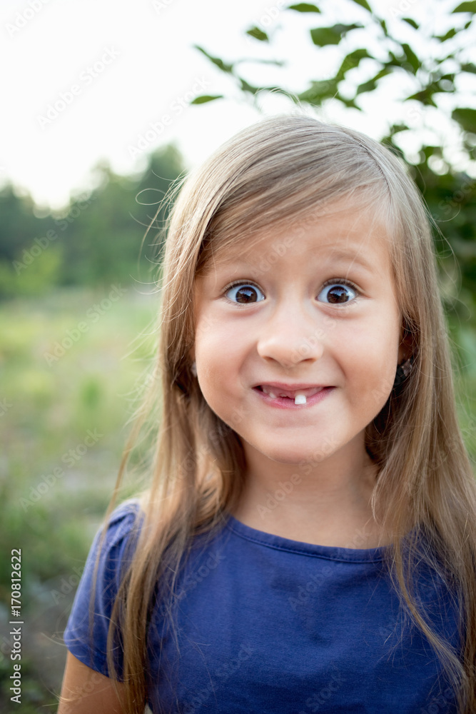 Young little girl without a front tooth in the countryside Young little girl without a front tooth in the countryside