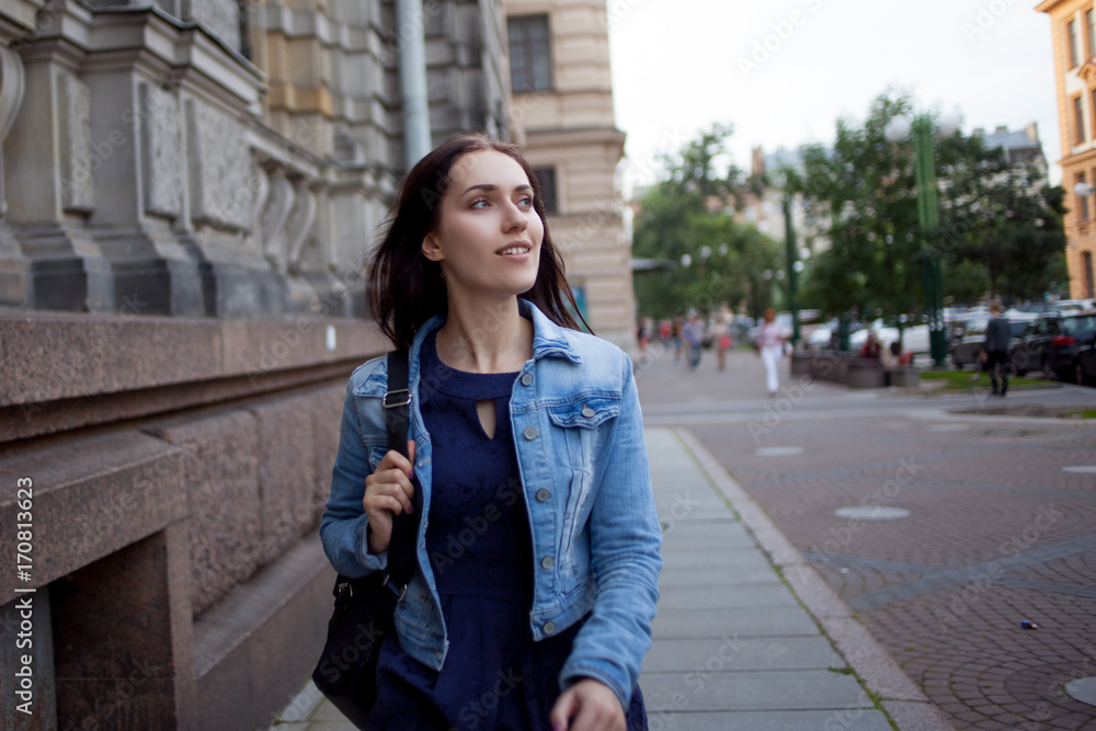 Fototapeta premium Beautiful young brunette with a backpack in the city