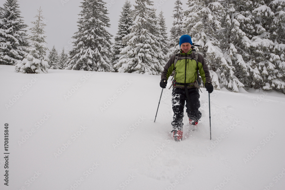 Adventurer man goes snowshoeing on deep snow