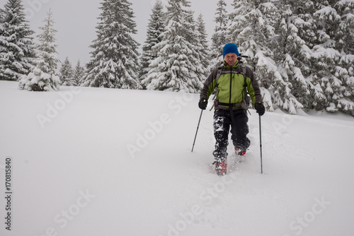 Adventurer man goes snowshoeing on deep snow