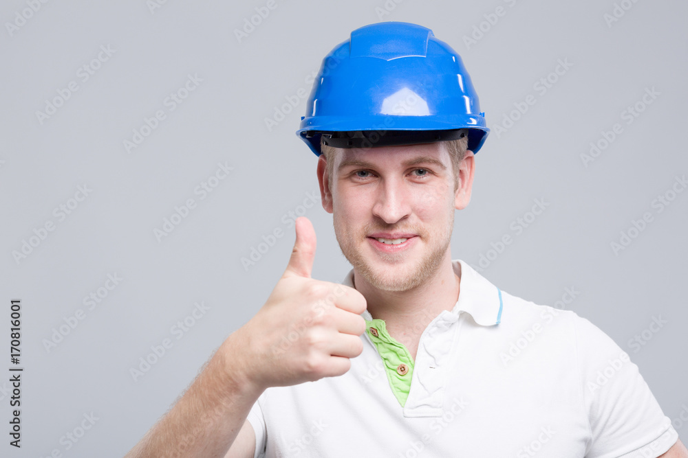 Junger dynamischer Mann mit Helm zeigt Daumen hoch Junger dynamischer Mann mit Helm zeigt Daumen hoch