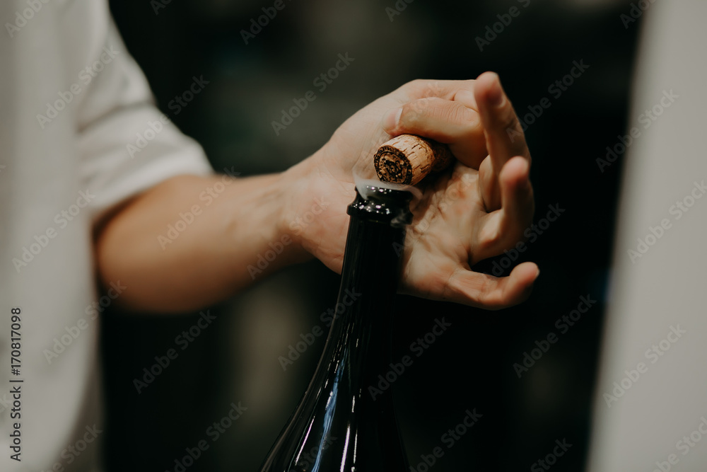 Fotografie Sommelier opening wine bottle in the wine cellar