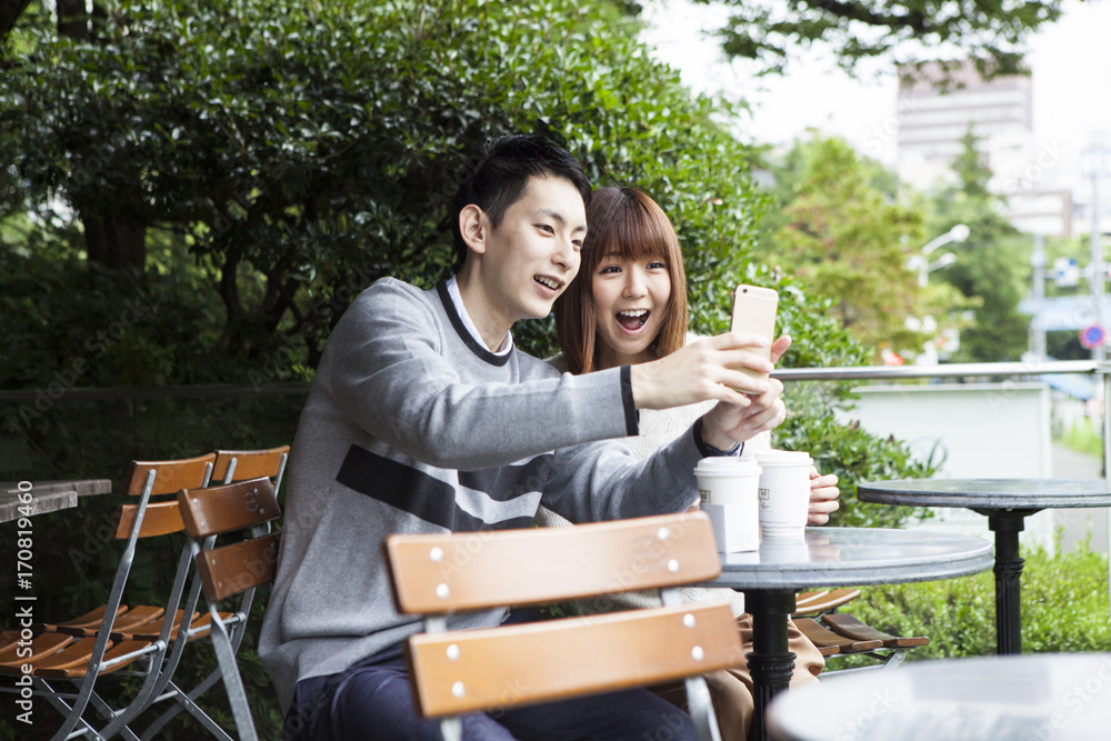 A young couple trying to take pictures on the cafe terrace A young couple trying to take pictures on the cafe terrace