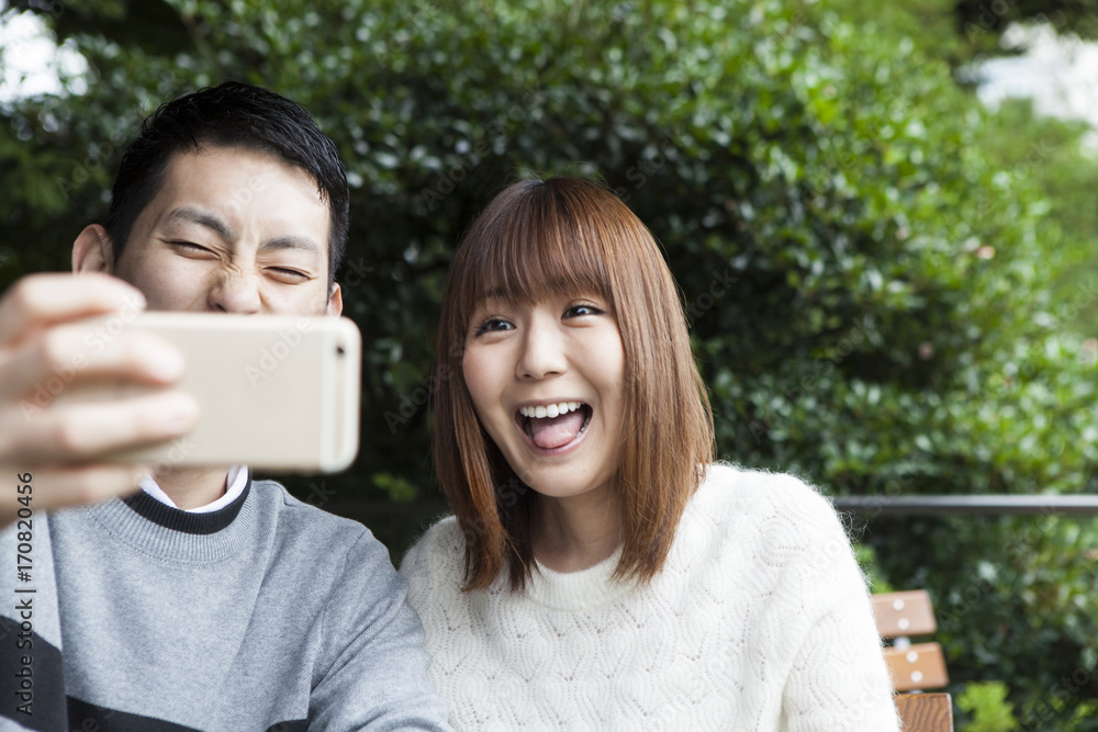 Young couple shooting pictures of funny faces at the cafe terrace Young couple shooting pictures of funny faces at the cafe terrace