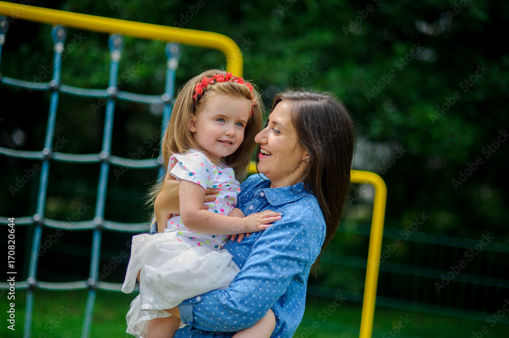 The young woman holds the little daughter on hands.