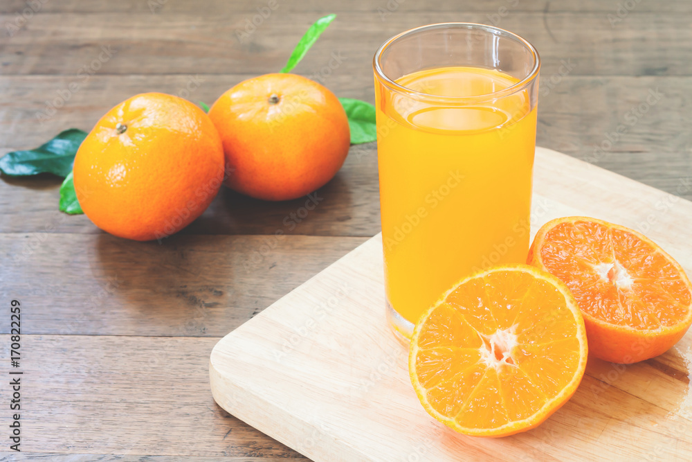 Naklejka premium Orange juice with fresh oranges on wood table, Autumn and fall season