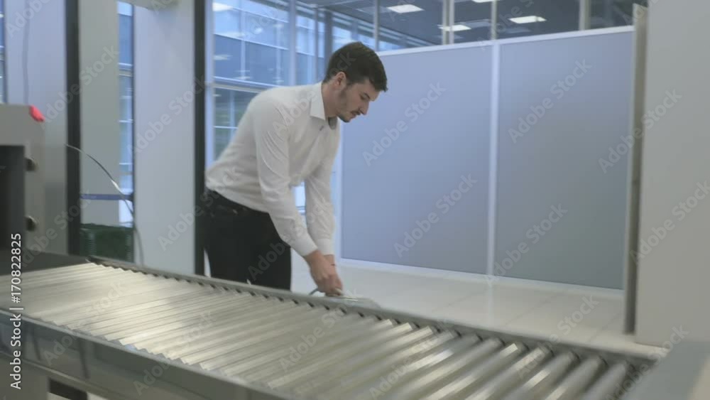 Businessman wait for luggage after scanning through x-ray scanner in the airport Businessman wait for luggage after scanning through x-ray scanner in the airport