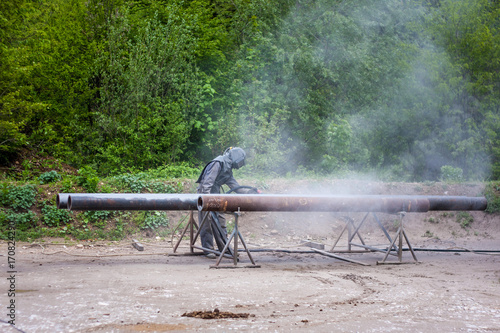 Sandblasting metal pipes outside.