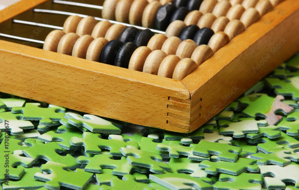 wooden abacus on pile of green puzzle wooden abacus on pile of green puzzle