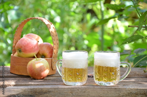 Two Glasses of cider with apples on rustic wooden background