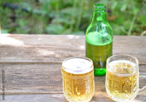 Two Glasses of cider or light beer and bottle on rustic wooden background octobcrfest photo