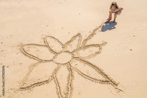 enfant dessinant sur le sable photo