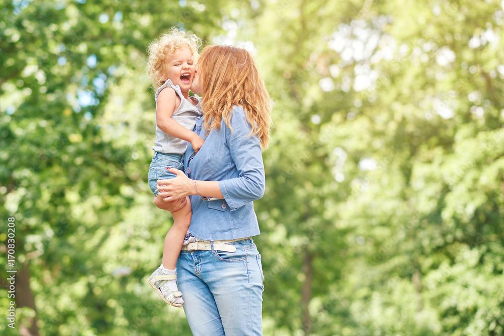Shot of a loving mother holding her cute baby girl kissing her on a cheek while outdoors at the park copyspace motherhood parent happiness love family children kids concept. Shot of a loving mother holding her cute baby girl kissing her on a cheek while outdoors at the park copyspace motherhood parent happiness love family children kids concept.